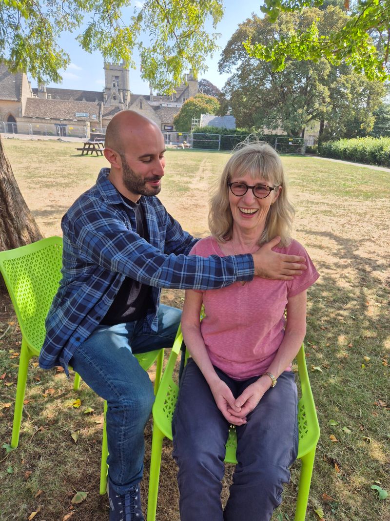 Simon teaching an Alexander Technique lesson, the student seated and smiling